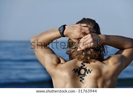 stock photo : muscular surfer boy with tribal tattoo and a clock on the 