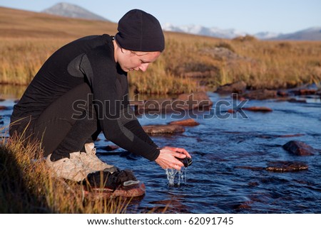 Female Hiker is washing her clothes on a little river in the evening light