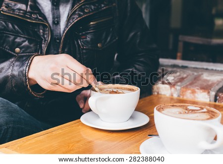 Man stirring coffee at a cafe