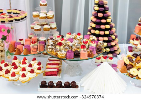 Wedding decoration with colorful cupcakes, eclairs, souffle, meringues, muffins and macarons. Elegant and luxurious event arrangement with sweets. Wedding dessert table