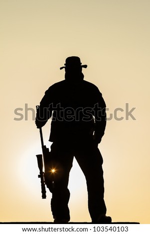soldier standing in the sun with a rifle resting with the flash of the sun