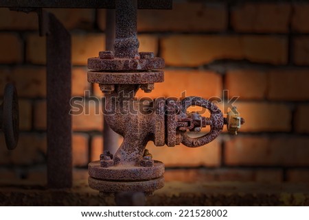 old broken gate valve in front of a brick wall with artificial vignetting