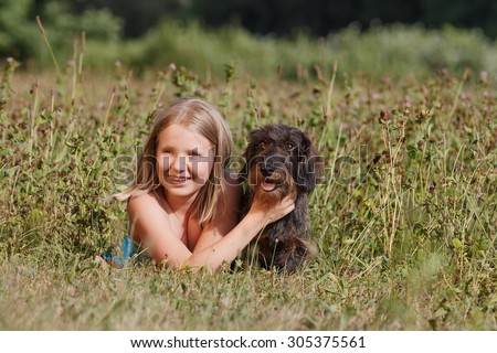 Pretty girl lying on the grass hugging dog