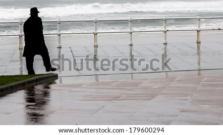 Man walking in a raincoat and hat