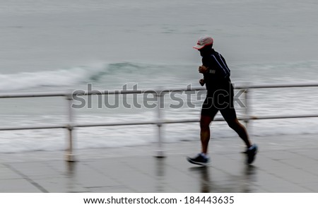 Young man with raincoat running around town
