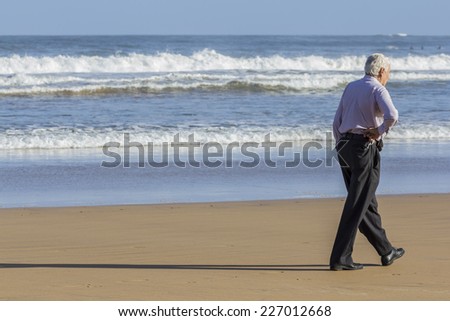 Man walking on the beach looking out to sea