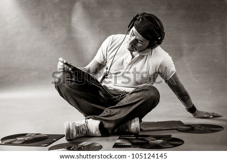 Black and white portrait of a dj sitting on the floor with vinyls