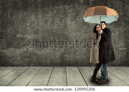 young couple searching protection under an umbrella