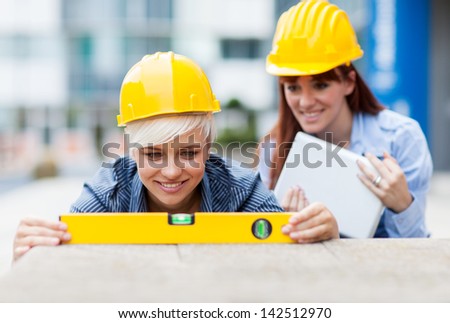 Photo of two female constructors working with a level on a wall