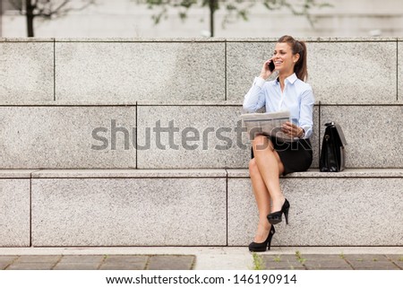 photo of brunette businesswoman sitting on stairs with newspaper