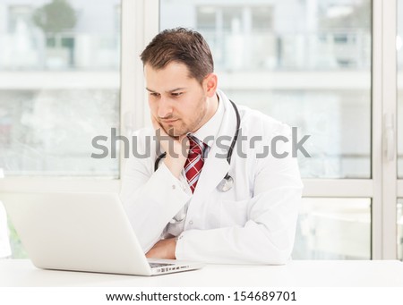 Doctor is sitting at his desk with notebook