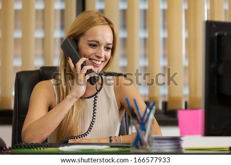 Smiling businesswoman working in the office while phoning