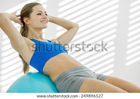 photo of attractive smiling woman doing workout with a gym ball