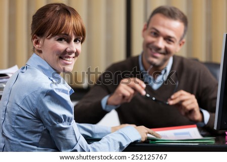 photo of two smiling colleagues in the office looking towards the camera