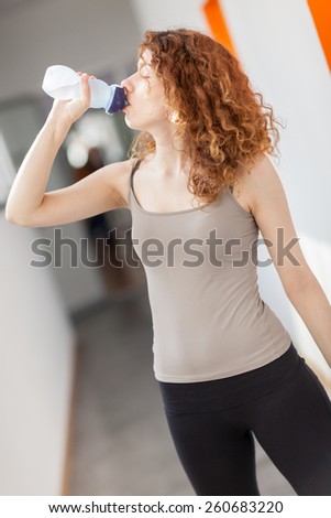 woman drinks water from a bottle in the gym