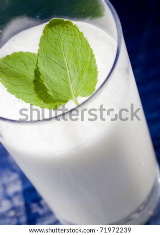 photo of hot milk in glass with two leaves of green fresh mint