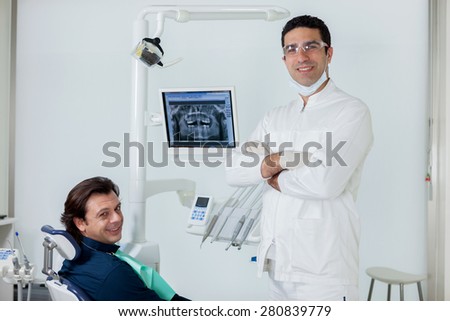Smiling dentist with his patient in the dental studio