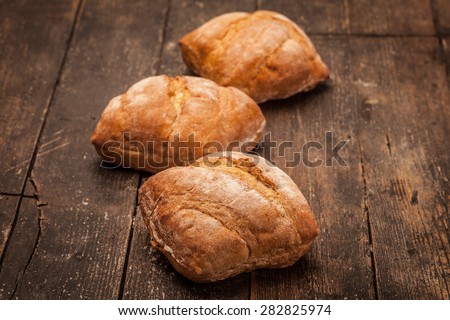 Photo of artisan ciabatta bread over over ancient wooden table