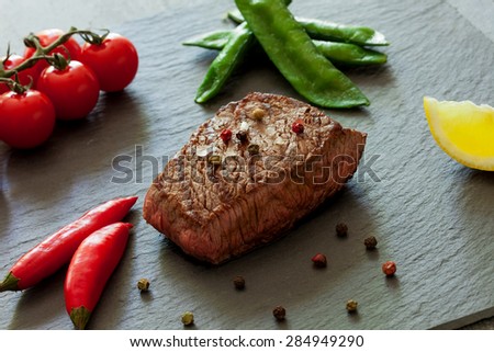 Delitious steak with vegetables over stone plate