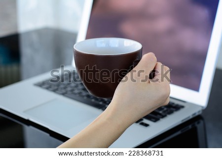 woman holding a cup of hot coffee in the office