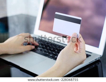 woman holding credit card in hand and entering information into a laptop, Shopping Online