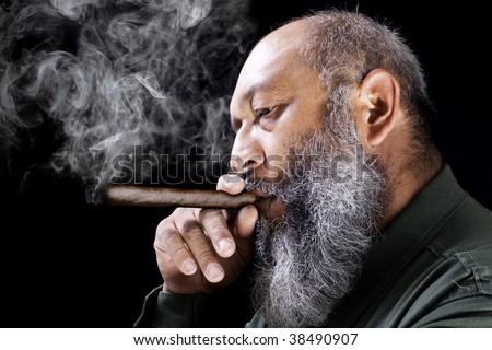 Stock image of adult male with long beard smoking cigar over dark background