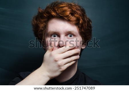 young redhead curly man surprised shut his mouth with hand