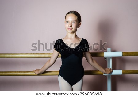 young girl ballerina in ballet school standing steel looking at the camera studio