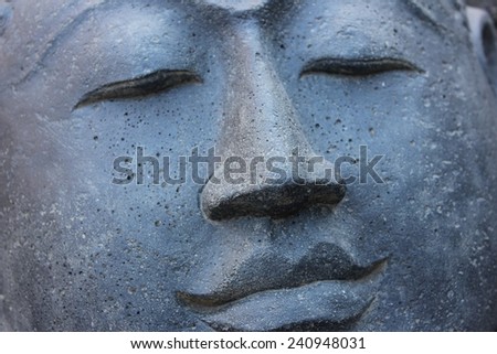 Smiling Stone Buddha Statue face with closed eyes from Indonesia looking to the right