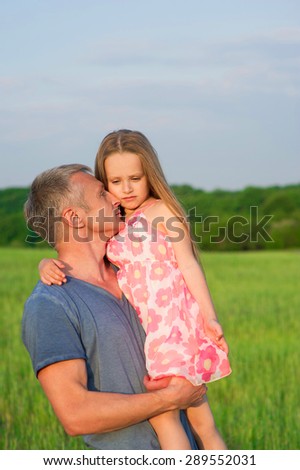 Dad hugs and holds daughter in his arms. Beautiful girl with long hair.