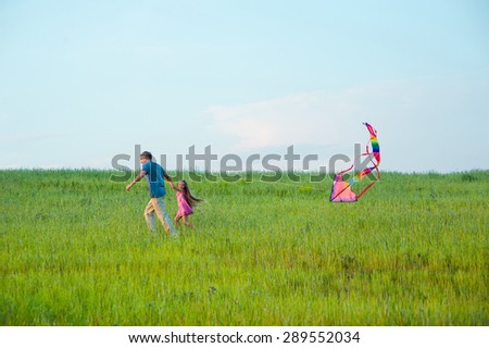 Dad and daughter fly a kite on a green grass. Father spending time with his daughter.