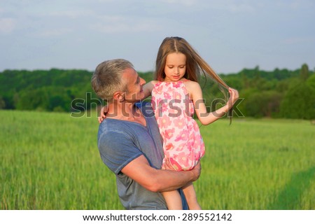 Dad keeps daughter in his arms. Beautiful girl with long hair.