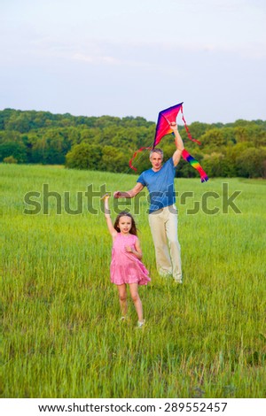 Happy dad and daughter in fild. Little girl and dad flying bright  kite.