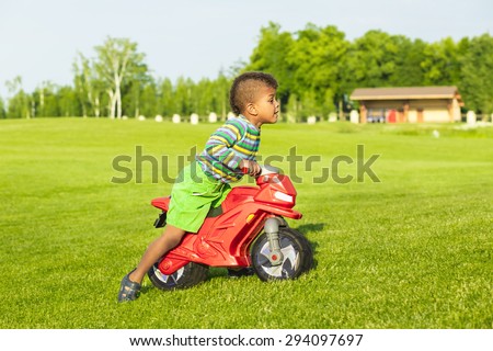 Cute afro boy on the red motorbike toy.