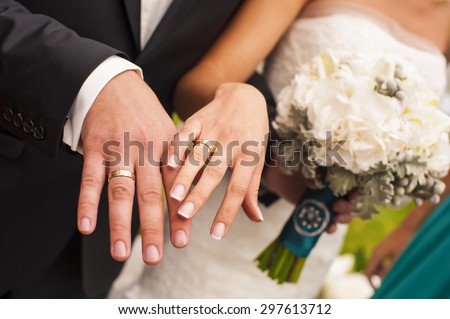 Newlyweds are showing their hands with wedding rings.