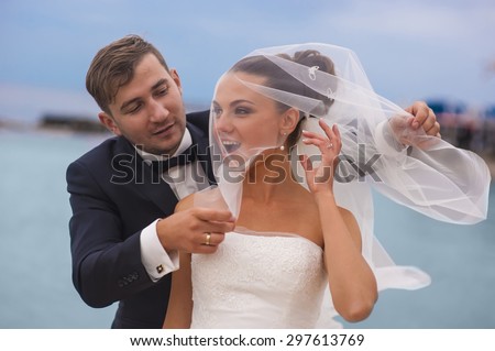 The groom is touching bridal veil of his beautiful bride.