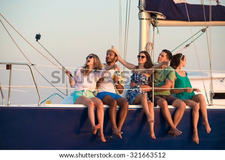 Merry company celebrates birthday on a yacht. Youth party on a yacht. Cruise on a sailing yacht. Friends making self on a yacht. Successful youth rests on a yacht.