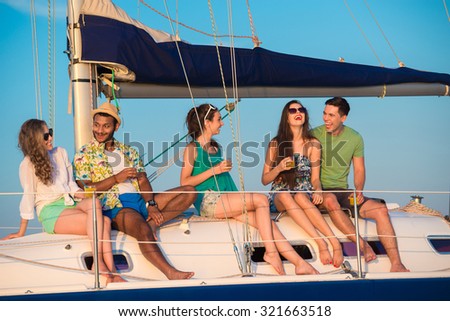 Cheerful young people relaxing on a yacht. Corporate party on a yacht. Friends spend a weekend on a yacht. Event on the yacht. Bandmates celebrating a birthday on a yacht.