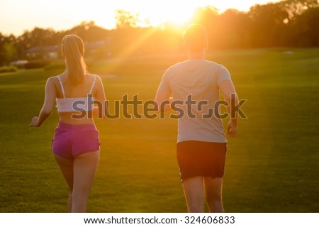 Guy and  girl running in the park. Morning running. Sports in nature. Morning cross-country on golf field. Boy and girl running cross-country.