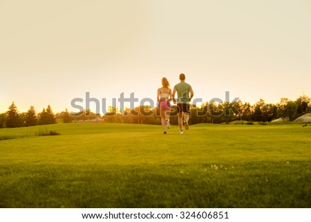 Guy and girl running on the green zone. Clean environment. Healthy lifestyle. Sports jogging outdoors. Running athlete.