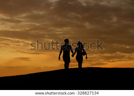 Loving couple of sportsmen walk on the evening hills. Silhouette of loving couple. Evening walk of husband and wife. Family walk.