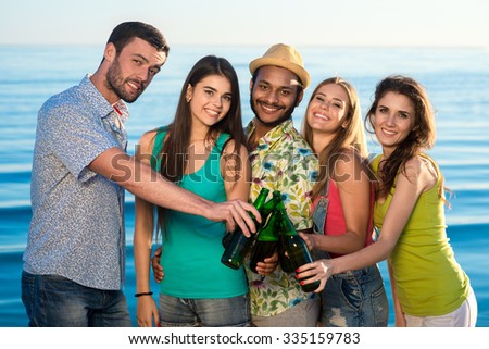 Leisure at sea. Weekend abroad. Youth party at sea. Funny guys and girls resting on vacation. Young people drink beverages on the beach.