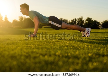 Guy shakes his muscles on the nature. Sports lifestyle. Young man engaged in sports in the street. Sports ground on nature.
