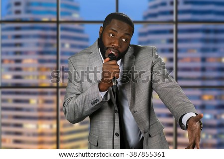 Black stand-up comedian. Evening comedy show on television. Comedian on urban background. Telling jokes on stage.