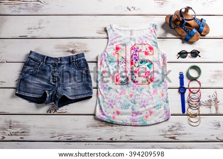Lady's outfit with jeans shorts. Woodern showcase with female outfit. Casual outfit for teenage girls. Colorful tank top and accessories.