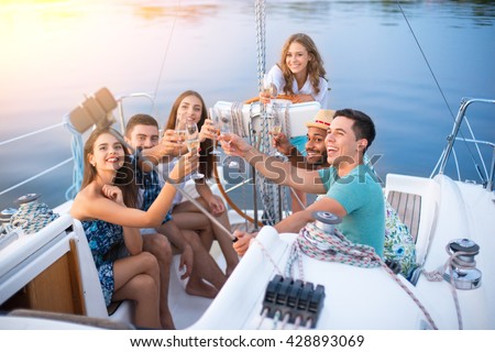 People with drinks taking selfies. Guys take selfies on yacht. Weekend party at sea. Friendly atmosphere and honest smiles.