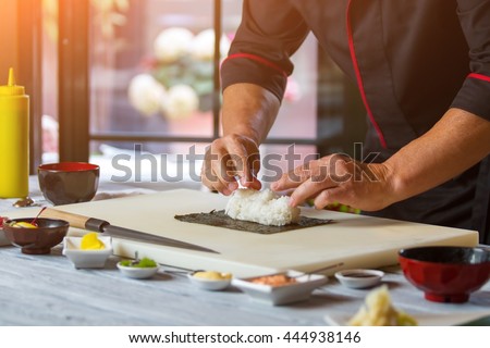 Nori and white rice. Man\'s hands touch rice. Chef starts cooking sushi. Simple recipe of hosomaki rolls.