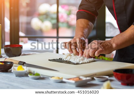 Male hands touch rice. White rice on nori leaf. Basic ingredients for sushi. Kitchen of japanese restaurant.