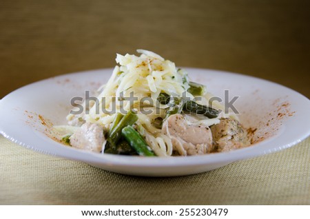 spaghetti with beans and chicken in a cream sauce topped with cheese on a white round plate