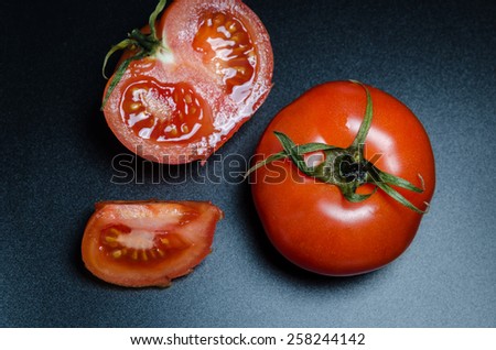 whole and sliced tomatoes on a black matte background